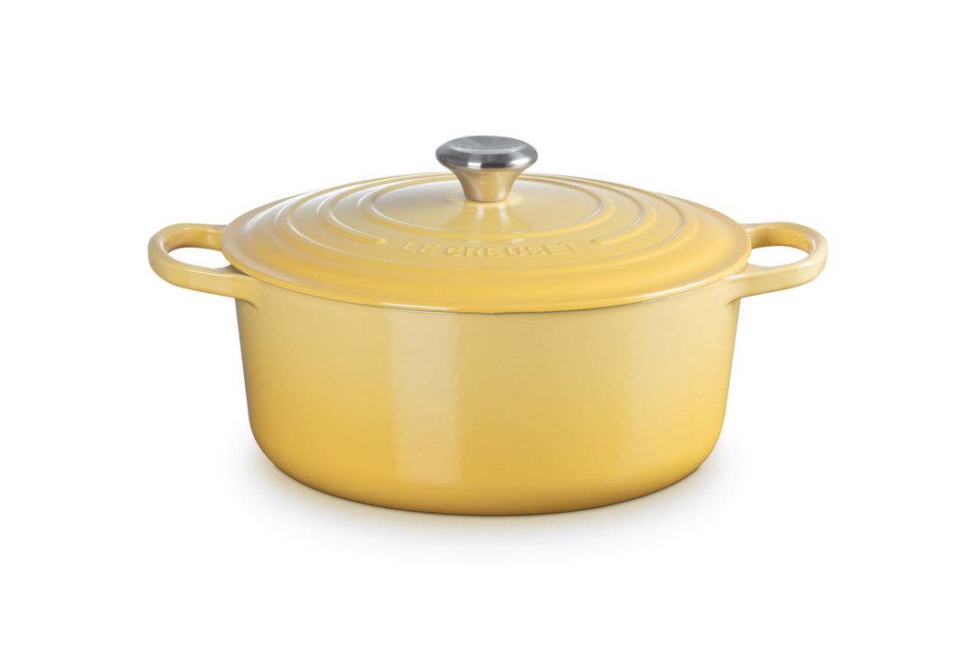 Yellow enameled cast iron Dutch oven with a lid on a white background