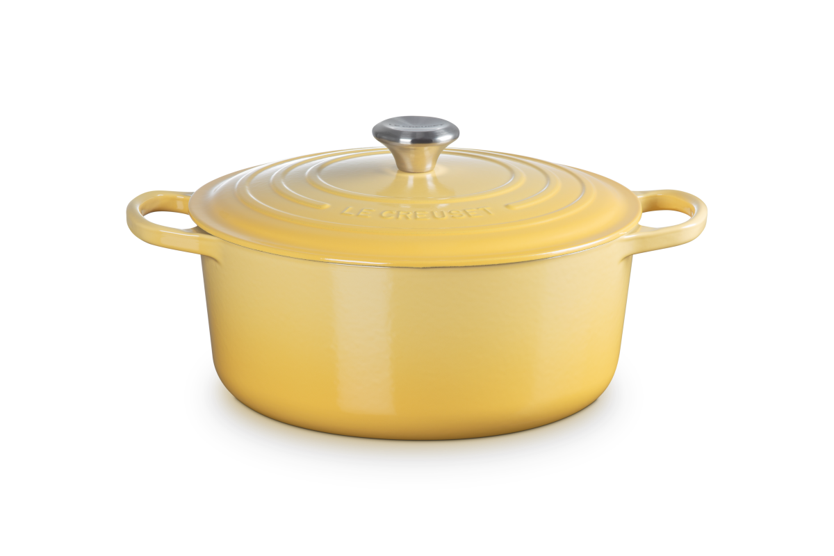 Yellow enameled cast iron Dutch oven with a lid on a white background