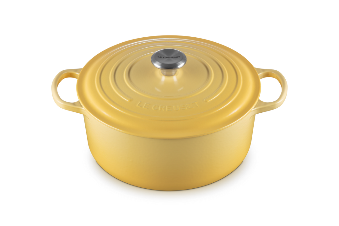 Yellow cast iron cookware pot with lid on a white background