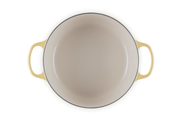 Beige enameled cast iron skillet with yellow handles on a white background