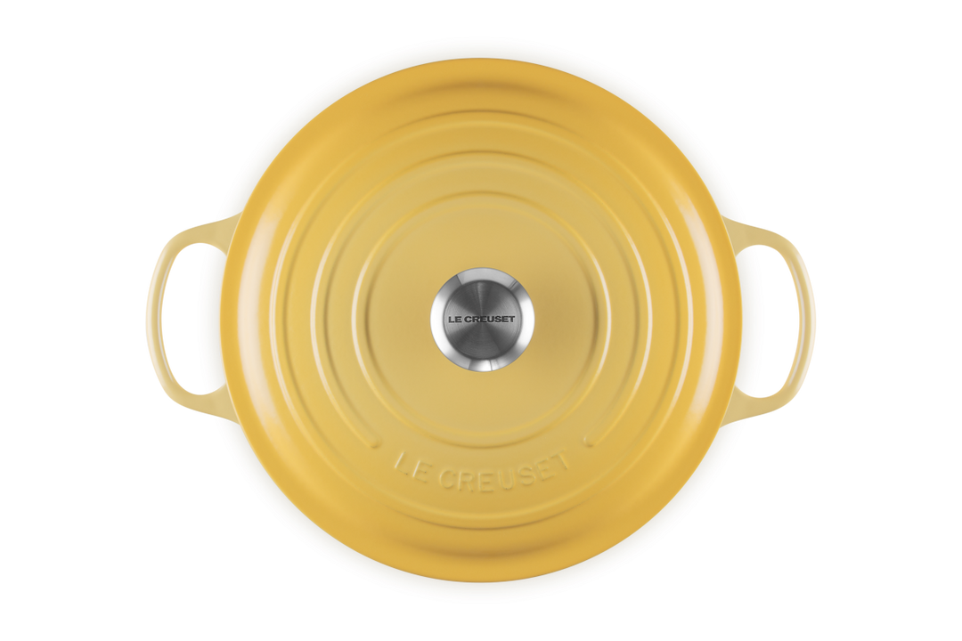 Yellow round dutch oven with handles on a white background