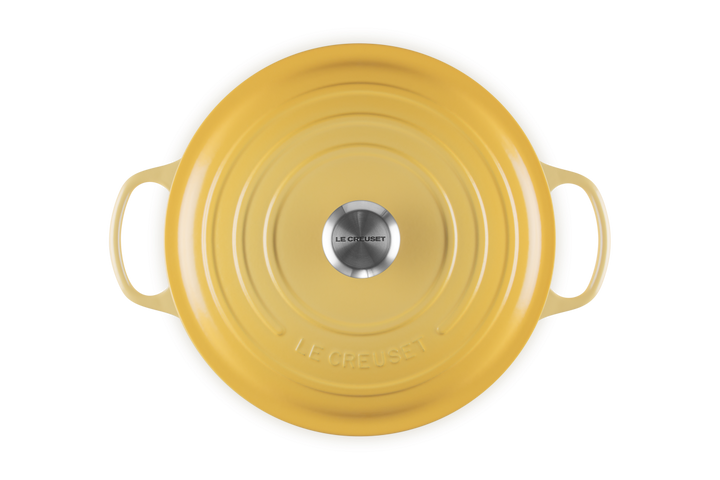 Yellow round dutch oven with handles on a white background