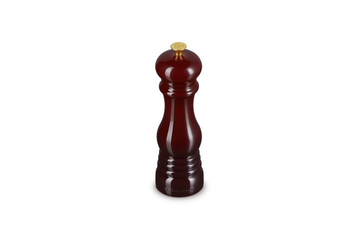 Le Creuset garnet pepper grinder on a white background