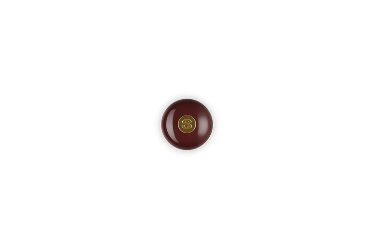 Top view of burgundy salt mill with gold knob on a white background