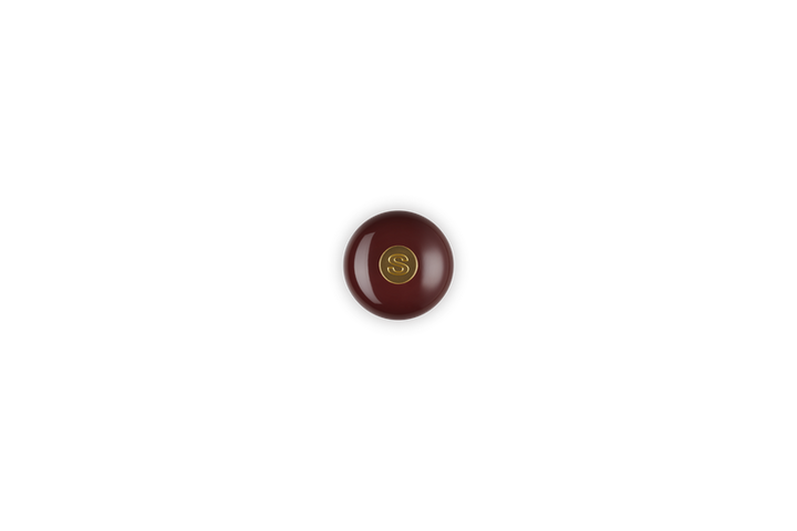 Top view of burgundy salt mill with gold knob on a white background