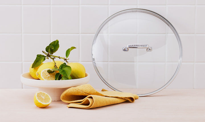 Clear glass lid on a kitchen counter with lemons and a yellow cloth.