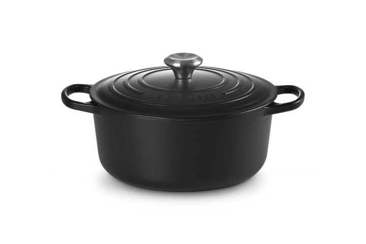 Black cast iron cookware pot with lid on a white background