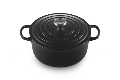 Black cast iron cookware pot with lid on a white background