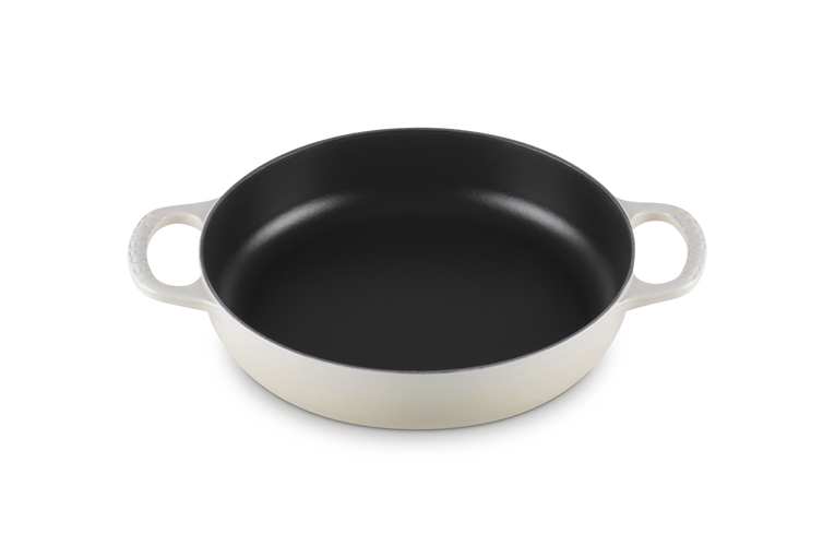 Le Creuset pan with white handles on a white background