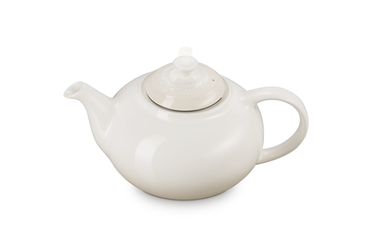 Le creuset cream ceramic teapot with a lid on a white background
