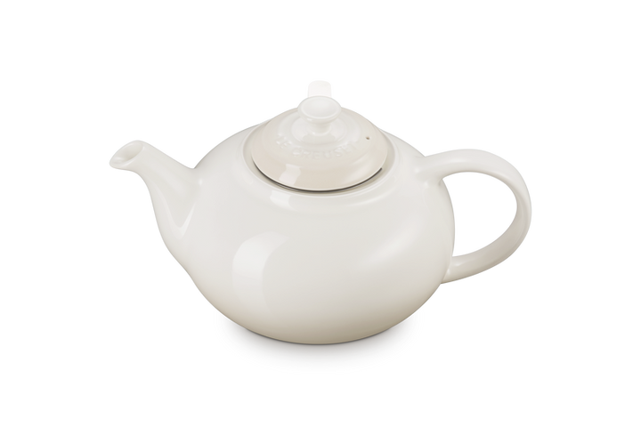 Le creuset cream ceramic teapot with a lid on a white background