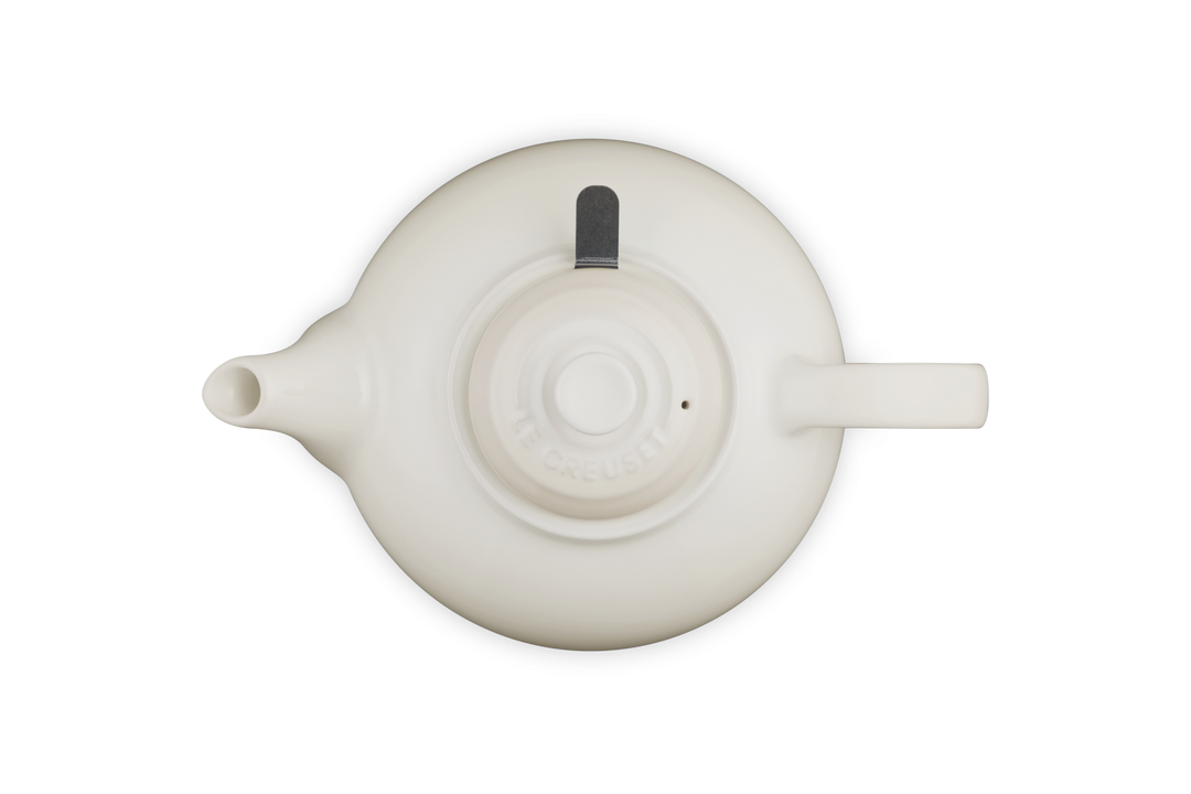 Le Creuset cream ceramic teapot on a white background