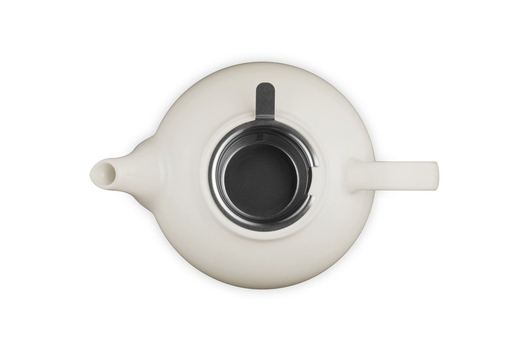 Le Creuset cream ceramic teapot with black interior on a white background