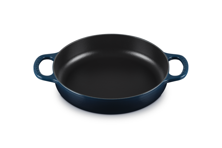 Dark blue round cast iron dish with handles on a white background