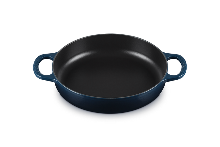 Dark blue round cast iron dish with handles on a white background