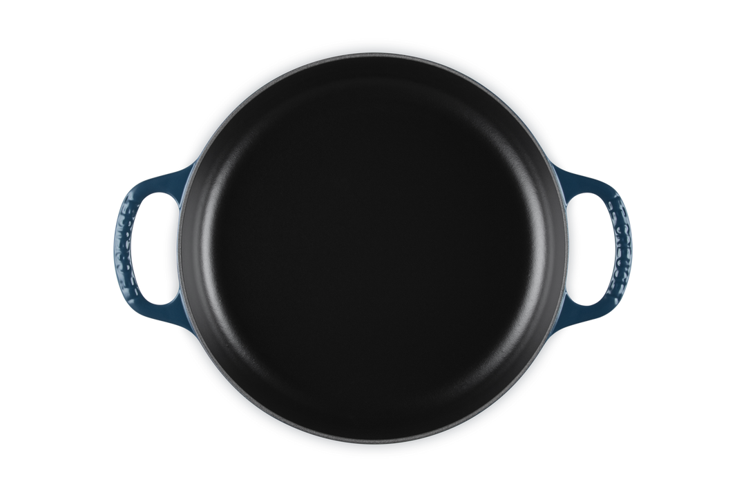 Dark blue cast iron skillet with blue handles on a white background