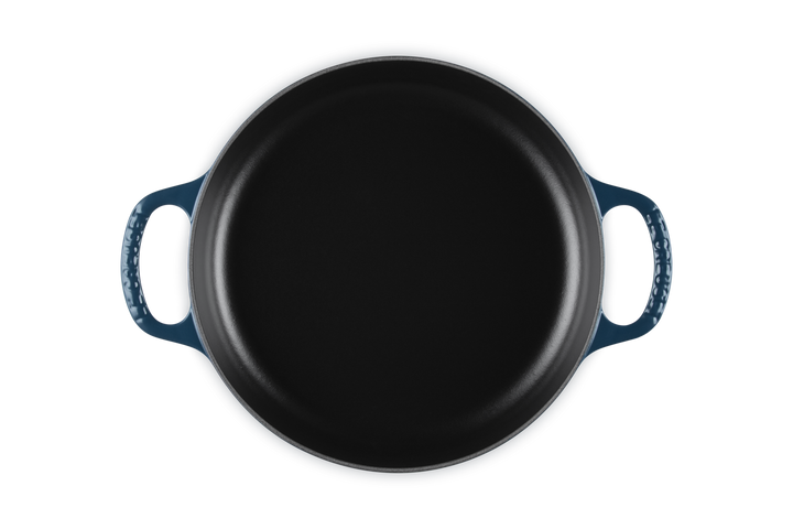 Dark blue cast iron skillet with blue handles on a white background