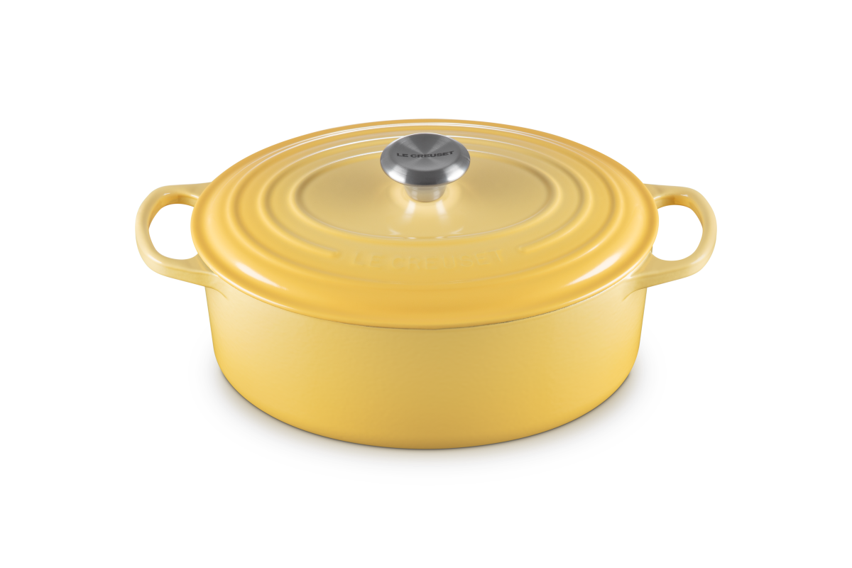 Yellow Le Creuset oval cast iron casserole on white background