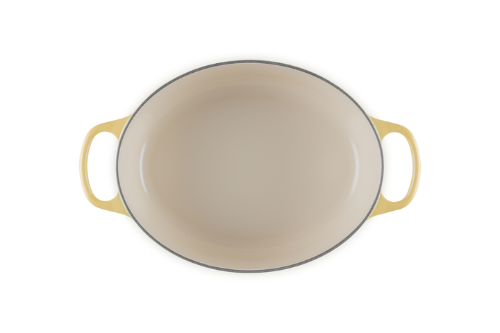 Beige enameled cast iron cookware with yellow handles on a white background