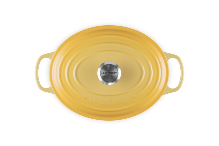 Yellow oval cast iron casserole with handles on a white background