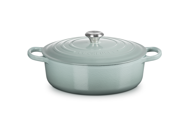 Light blue cast iron risotto pot with lid on a white background