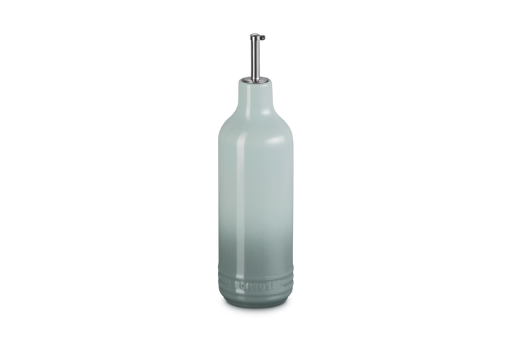 Light green ceramic oil bottle with a metallic cap on a white background