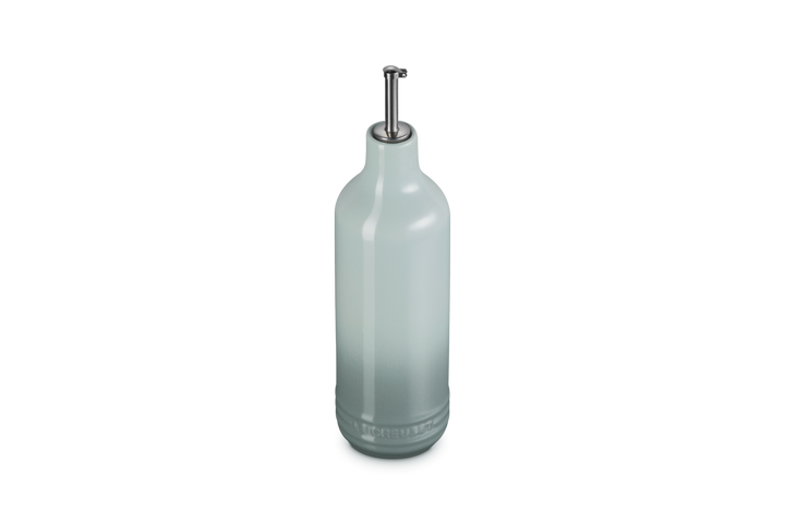 Light green ceramic oil bottle with a metallic cap on a white background