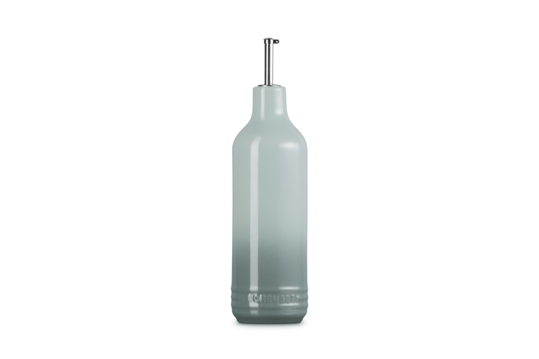 Light green ceramic oil bottle with a metallic cap on a white background