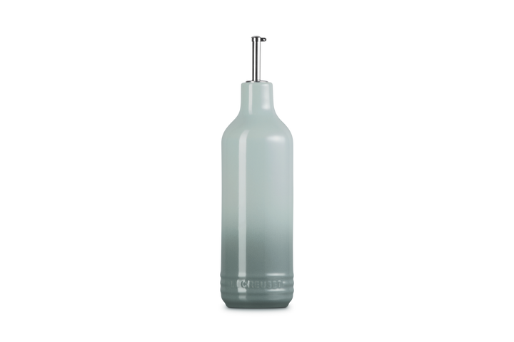 Light green ceramic oil bottle with a metallic cap on a white background