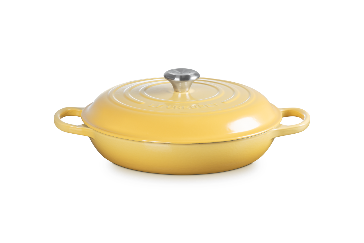 Yellow shallow casserole with a silver knob on a white background