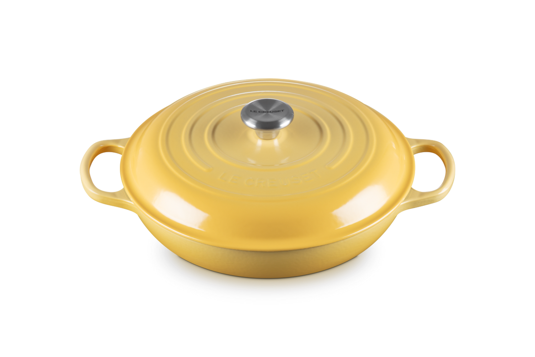 Yellow cast iron shallow casserole with a lid on a white background