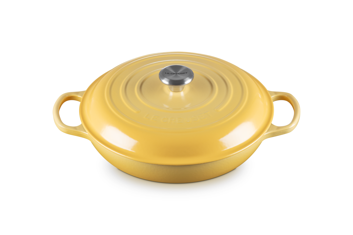 Yellow cast iron shallow casserole with a lid on a white background