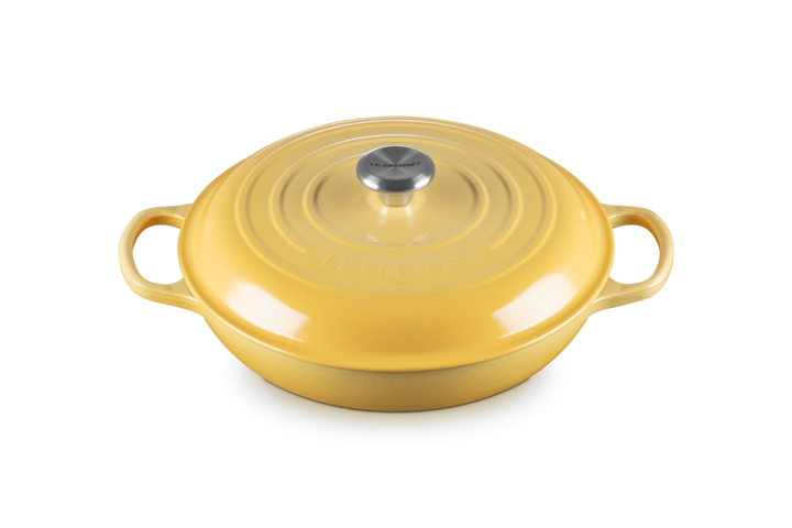 Yellow cast iron shallow casserole with a lid on a white background