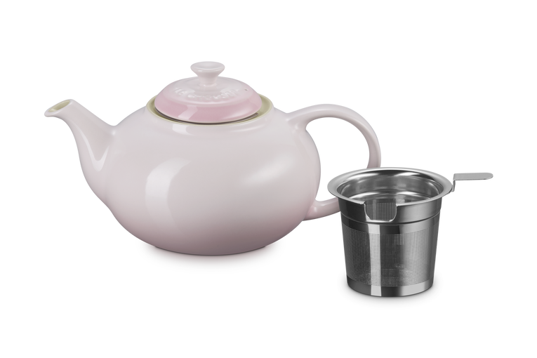 Pink teapot with a metal infuser on a white background