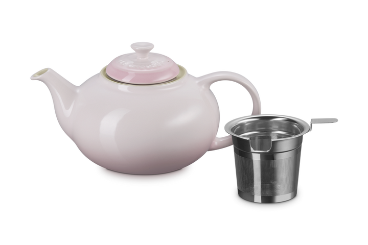 Pink teapot with a metal infuser on a white background