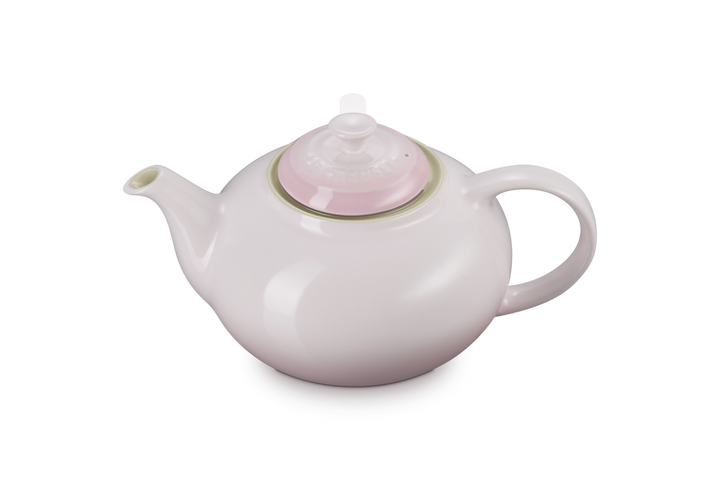 White teapot with a pink lid on a white background