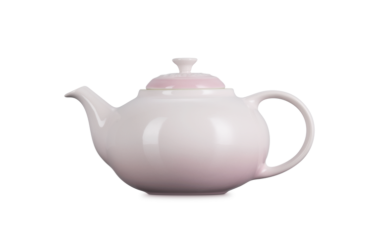 Pink Le Creuset teapot on a white background