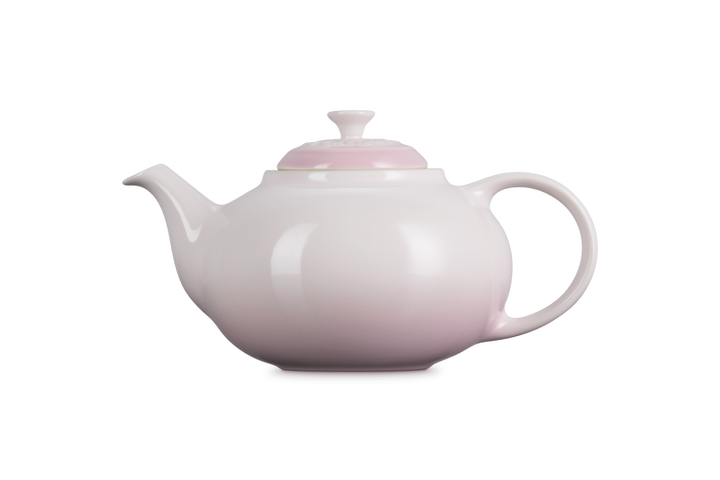 Pink Le Creuset teapot on a white background
