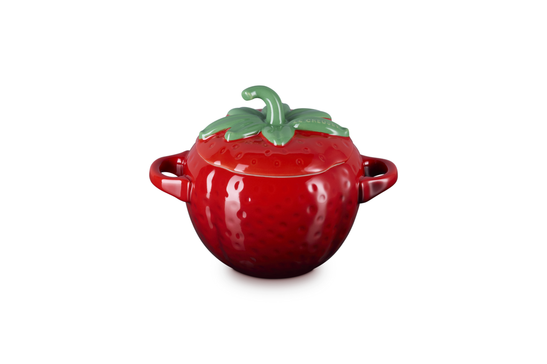 Red ceramic pot shaped like a strawberry with a green lid on a white background