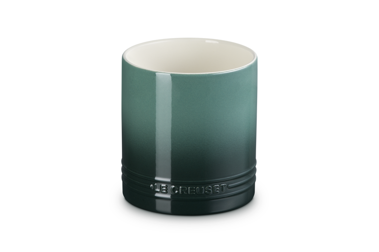 Green ceramic utensil holder with a white interior on a white background