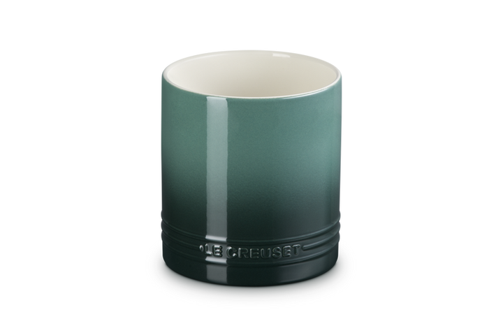 Green ceramic utensil holder with a white interior on a white background