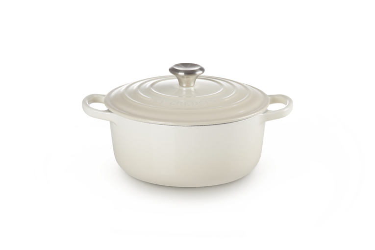 Cream enameled cast iron Dutch oven with a lid on a white background