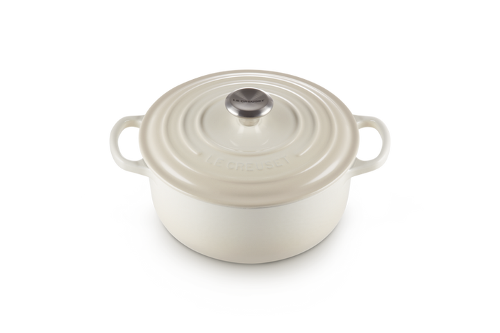 Cream enameled cast iron round Dutch oven on a white background
