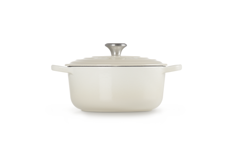 Cream enameled cast iron Dutch oven with lid on a white background