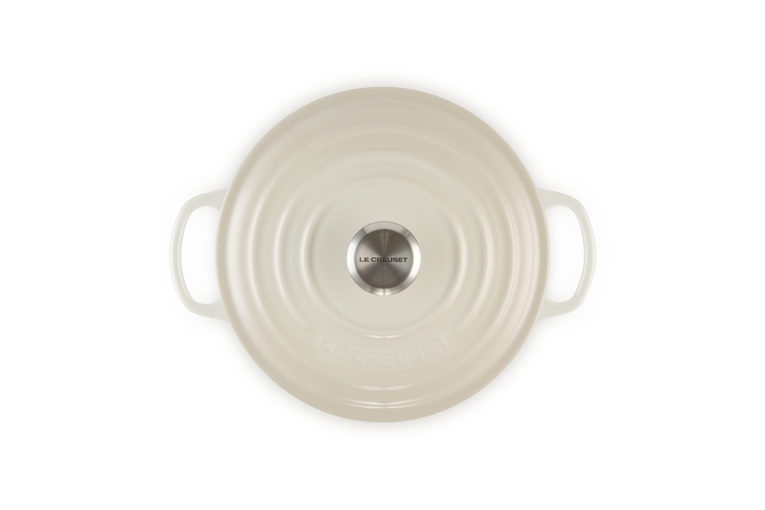 Cream round cast iron dish with handles on a white background