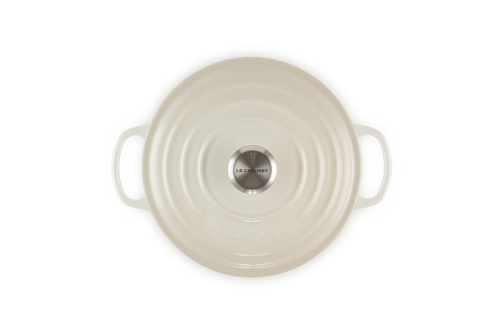 Cream round cast iron dish with handles on a white background
