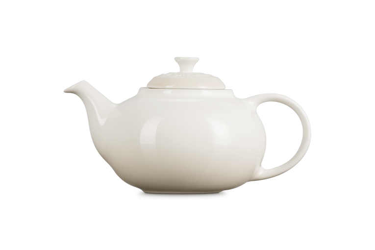Le Creuset cream ceramic teapot on a white background
