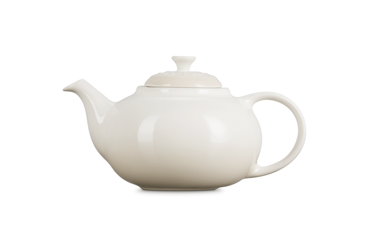 Le Creuset cream ceramic teapot on a white background