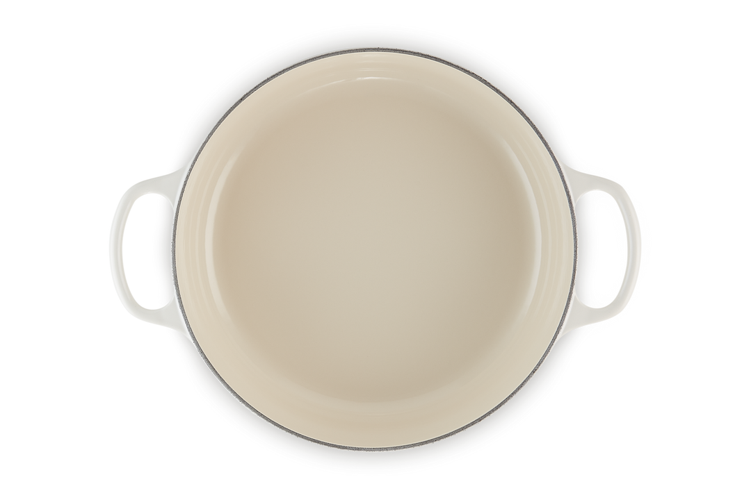 Beige enameled cast iron risotto pot with handles on a white background