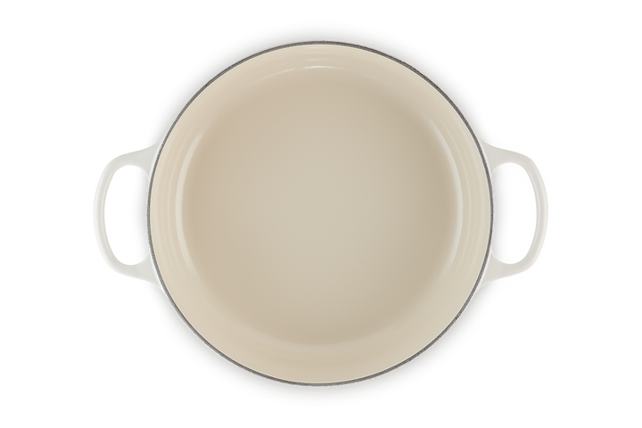 Beige enameled cast iron risotto pot with handles on a white background
